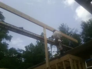 Carpenter setting a ridge beam over a new addition frame — Ice Dam Removal by Roofing Brothers in Lavonia
