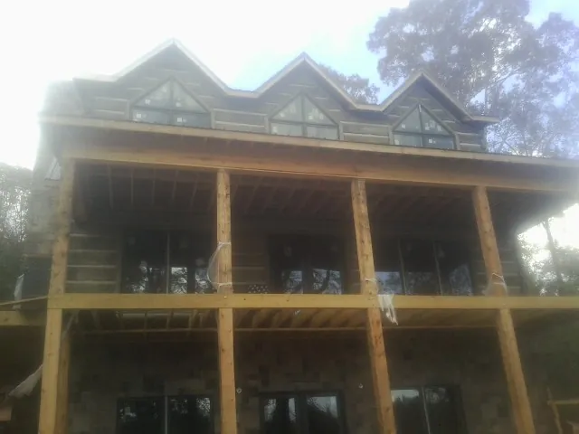 Dormers and porch framing on a large log home under construction — Roof Coating work by our crew in Lavonia