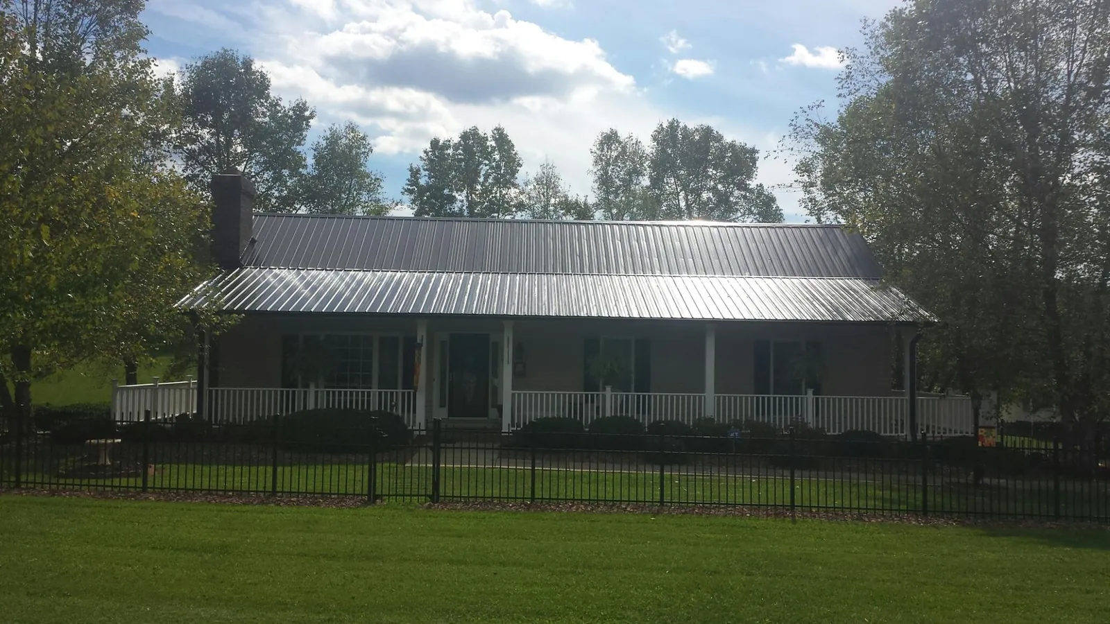 Gray metal roof on a brick ranch with a full width front porch — Gutter Guard Installation work by our crew in Lavonia