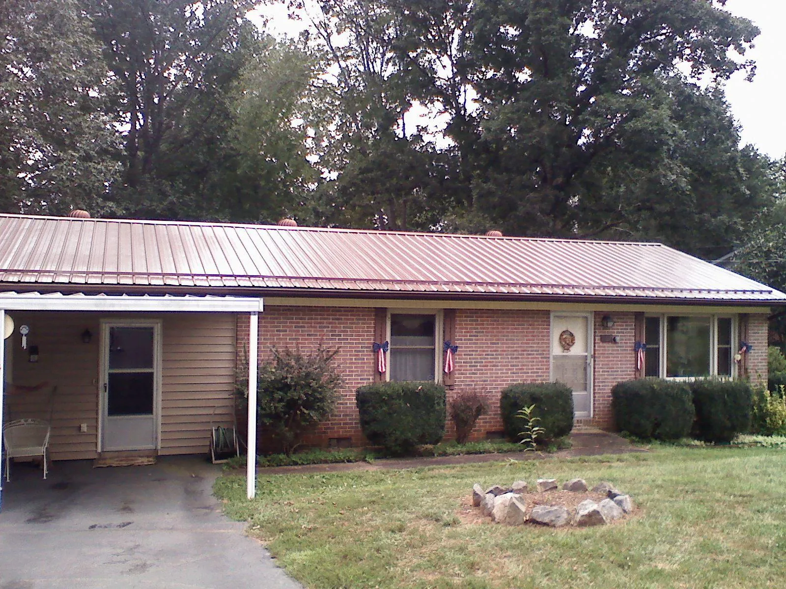 Bronze metal roof and carport on a brick ranch home — Roof Repair work by our crew in Lavonia