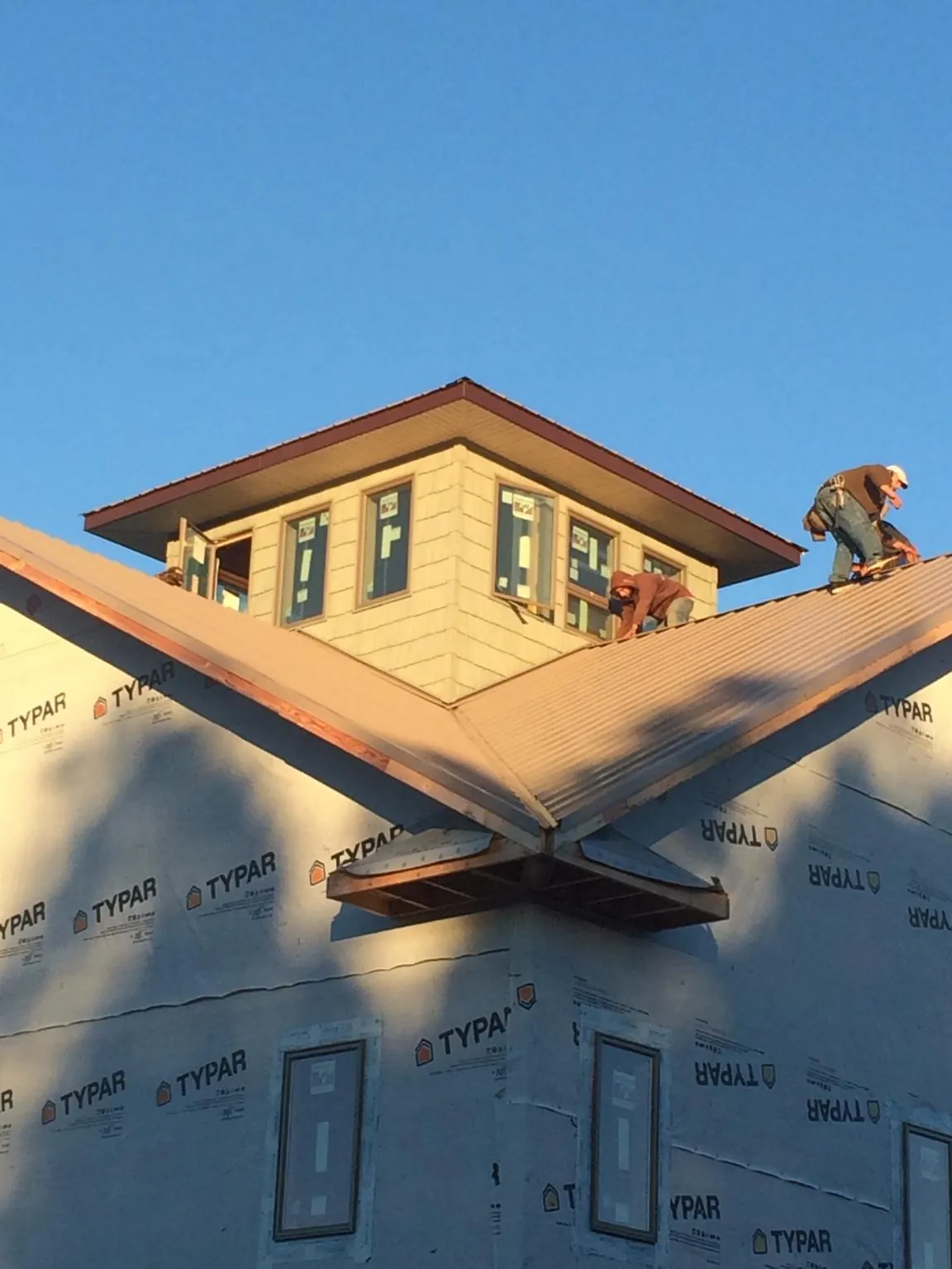 Roofers working around a rooftop cupola on a new metal roof at sunset — Roof Waterproofing in Lavonia by Roofing Brothers